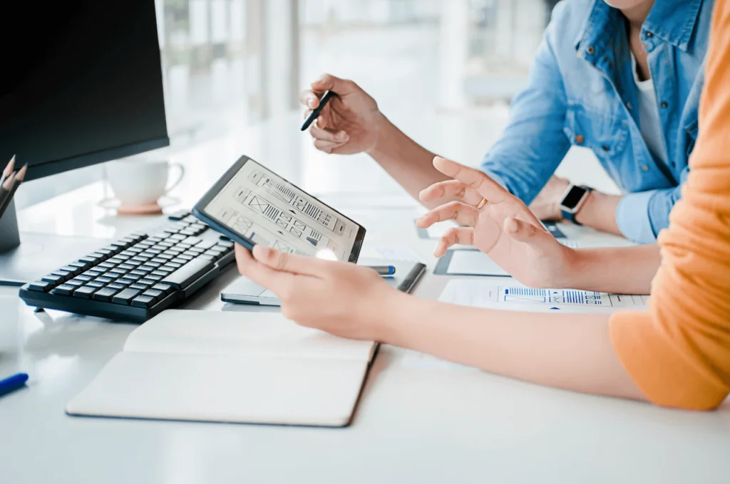 A picture of two people at a desk reviewing some design work on a tablet.