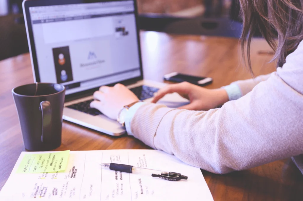 A picture of a small business owner at a table, working on her laptop.