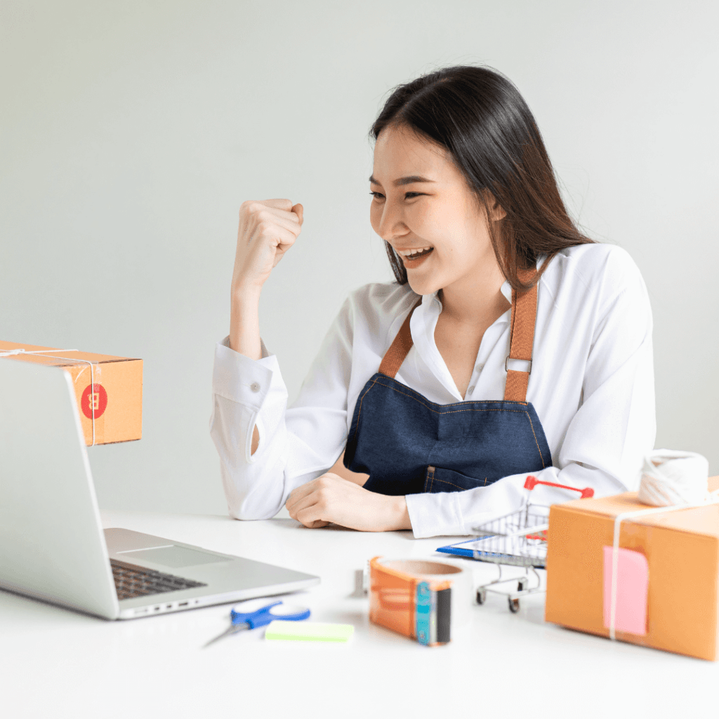 A female small business owner sitting at a desk and looking excited