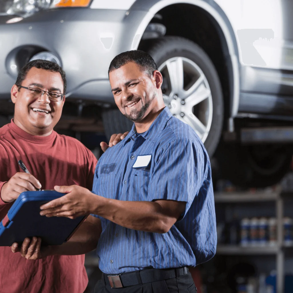 A mechanic signing a contract with a customer in front of a car