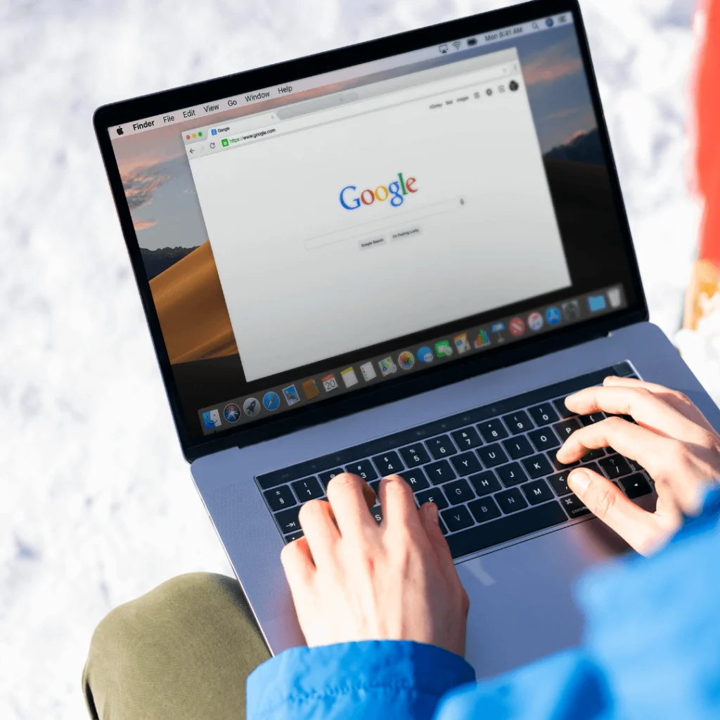 A closeup of someone on a laptop searching on Google's home screen