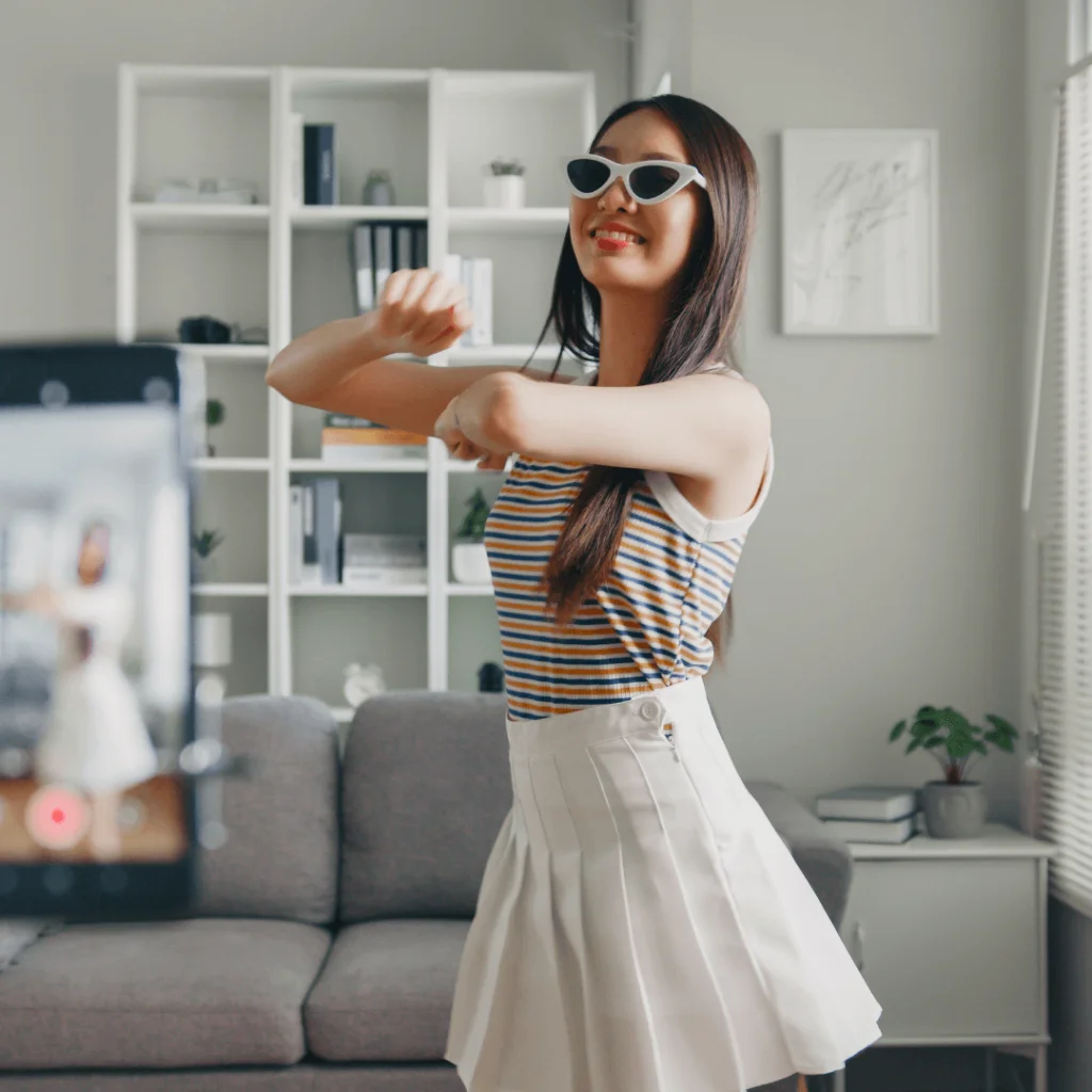 A young woman dancing in front of a phone for a TikTok video.