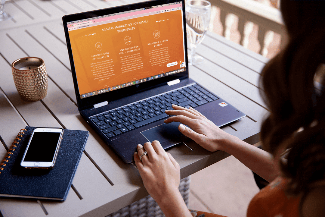 A woman sitting at a table working on web design on her laptop