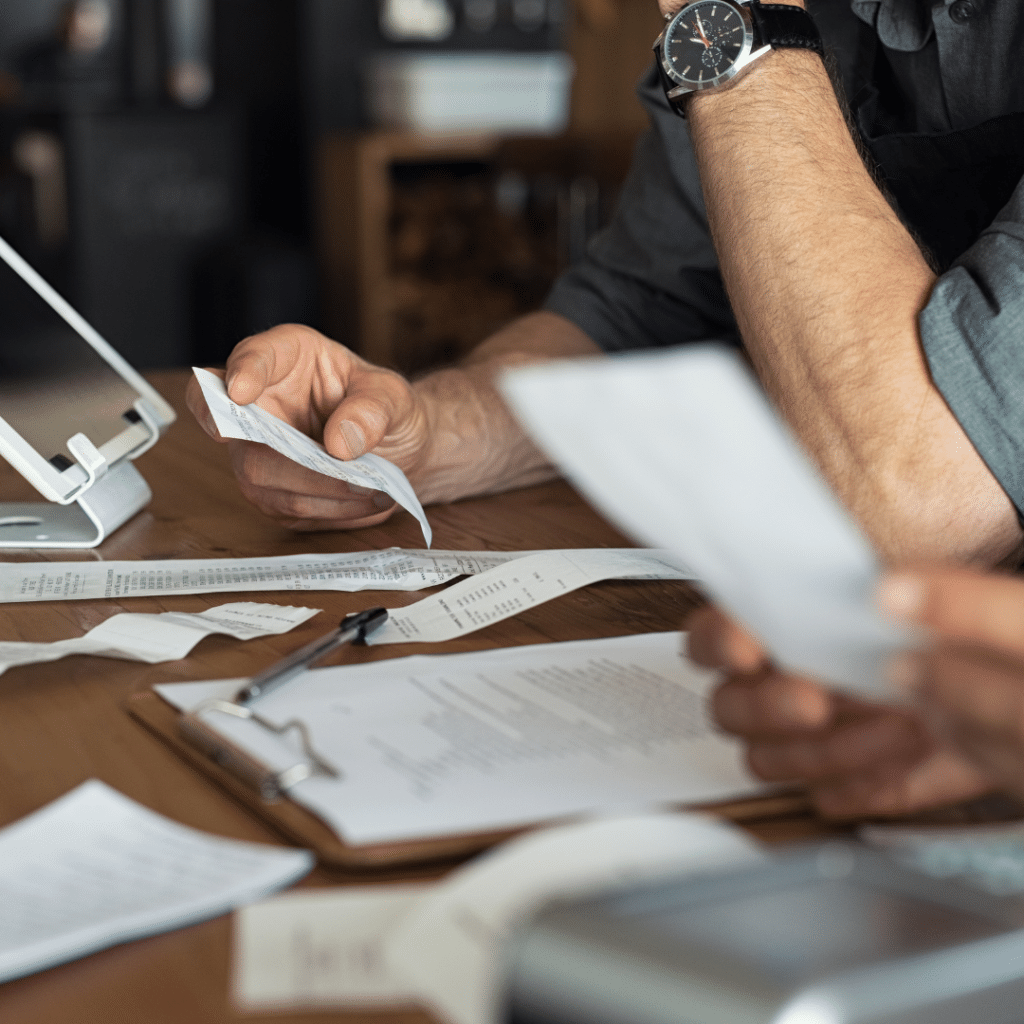 A man is looking over small business paperwork and receipts in an image for a blog about "Local SEO Tips to Dominate Your Market in 2025."